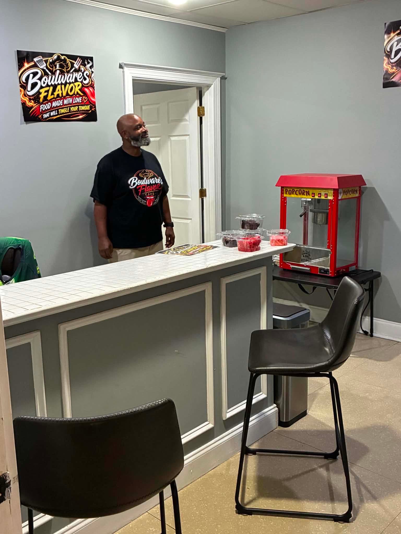 The owner behind the counter at Boulware's Flavor Café, wearing a Boulware's Flavor Café shirt